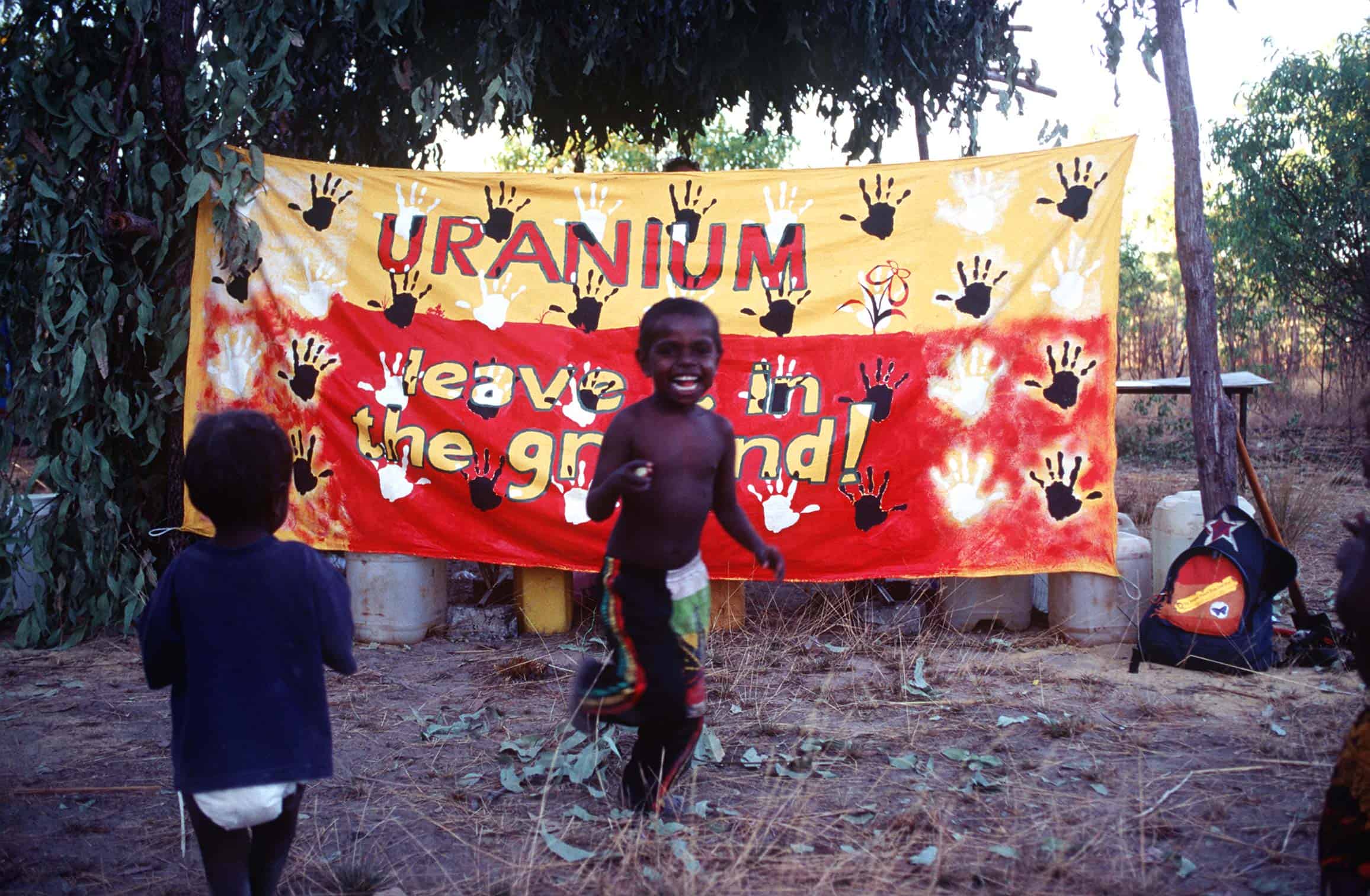 child running in front of banner that says Uranium leave it in the ground
