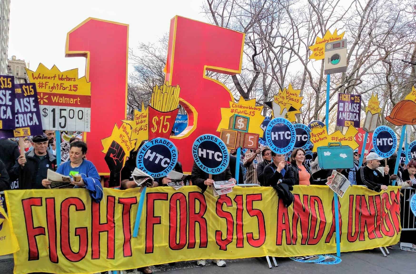 Protestors at a rally holding sign that says Fight for $!5 and a union. 
