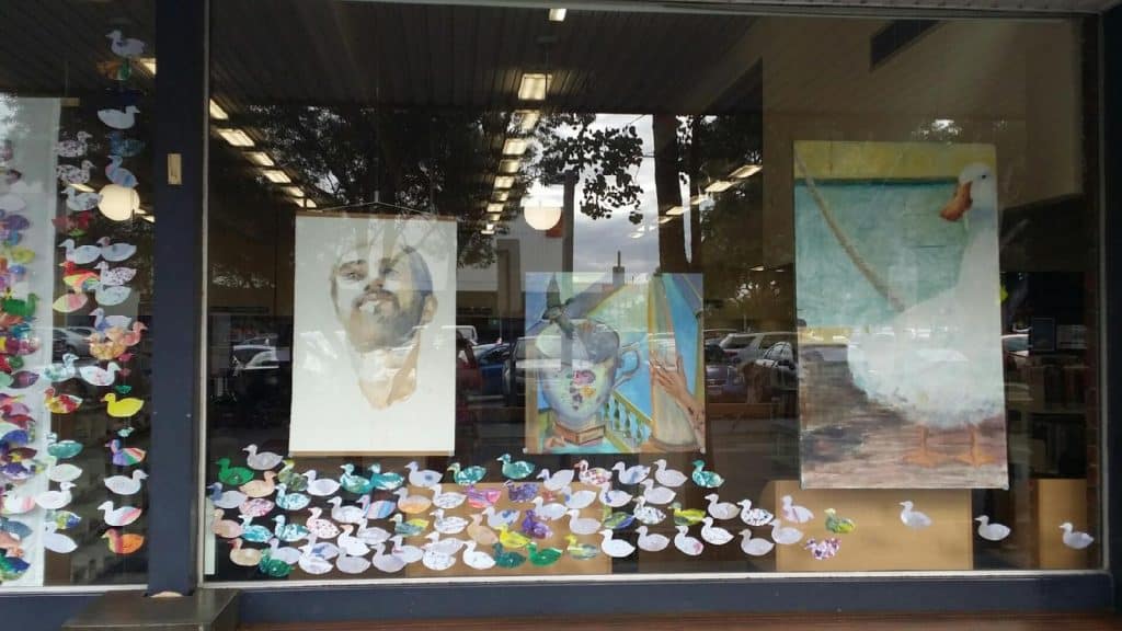 Window with crafted paper ducks and artworks.
