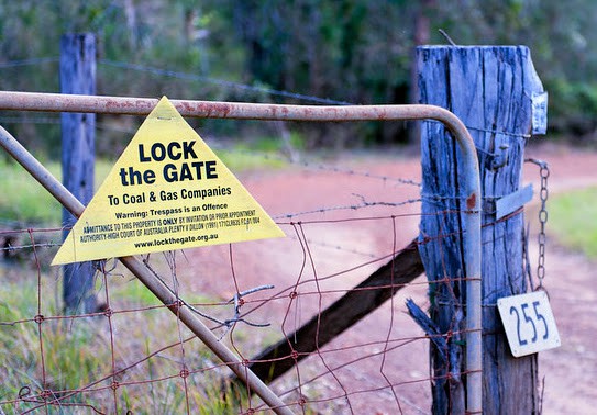 A lock the gate sign on a fence. The sign says Lock the Gate to Coal and Gas Companies - Warning Trepass is an offence.