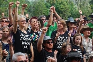 Protesters blockading at Bentley in NSW against the coal and gas industry in 2014. A group of people holding their fists up in the air wearing black tshirts with white writing that says Don't Frack with me