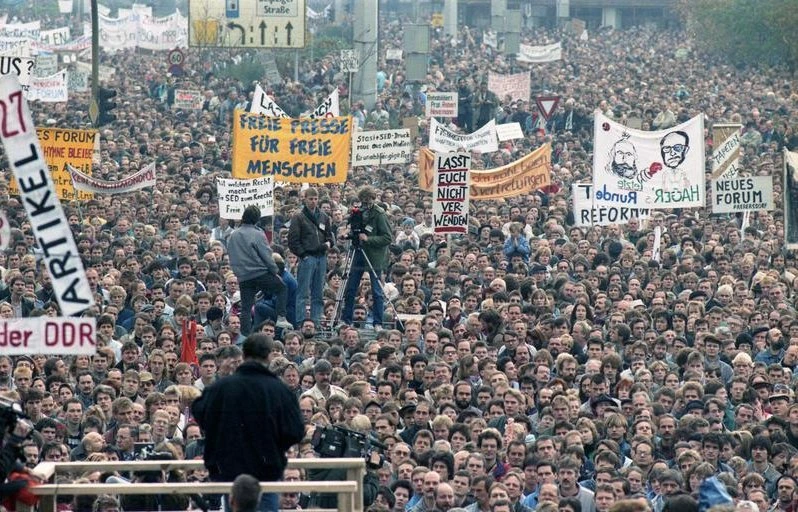 Thousands of protestors holding banners and signs in Berlin.|screenshot of the website - The Global Nonviolent Action Database - https://nvdatabase.swarthmore.edu/search/node?keys=|Black and white photo of student protestors holding signs walking down the street at the University of Dhaka campus.