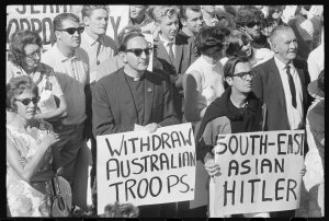 Protestors holding banners with words - Withdraw Australian troops - and - South Asia Hitler