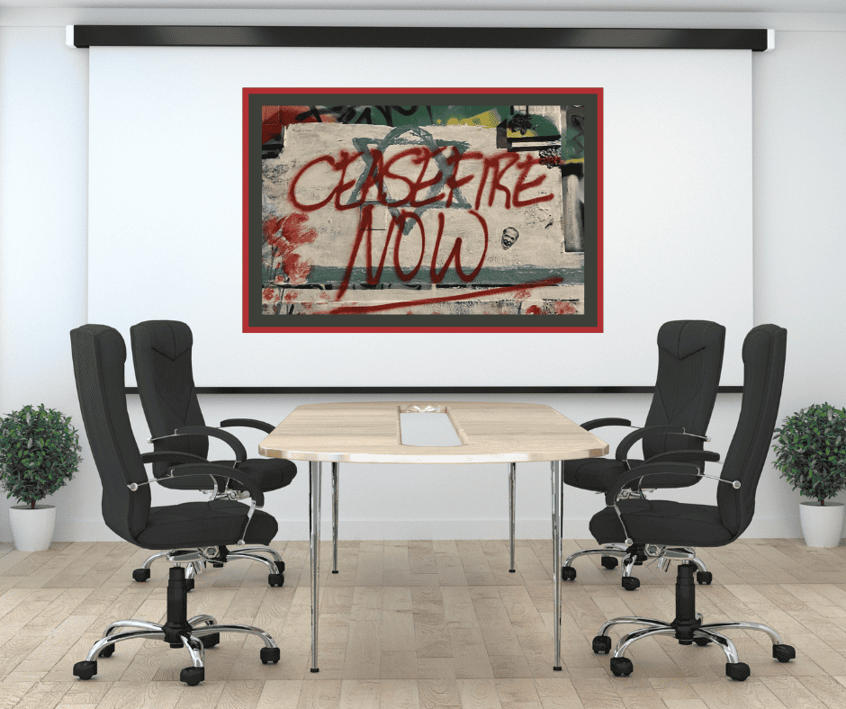 A table with four chairs set up for a board meeting. A screen at the front of the room has a photograph of street art reading 'Ceasefire Now'.|