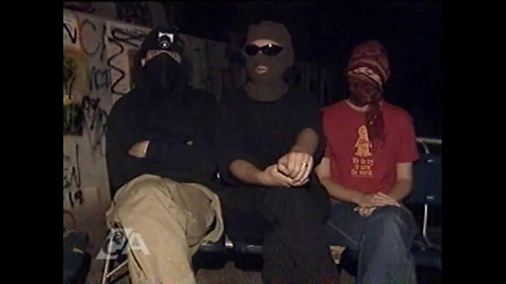 Three people sit wearing balaclavas.