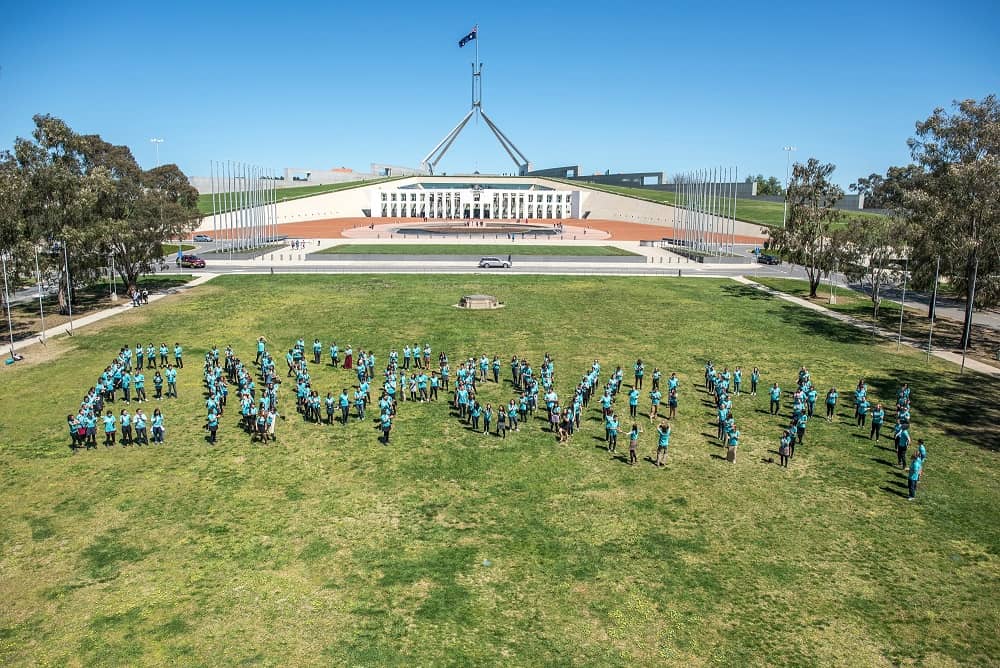 A group of young people spell out 'End Poverty' on the Australian Parliament House lawn.