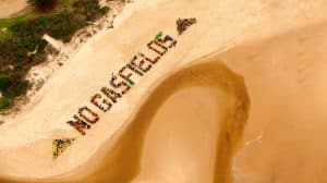 an aerial photo of a beach with words being made of by a mass of people. The words read No Gasfields
