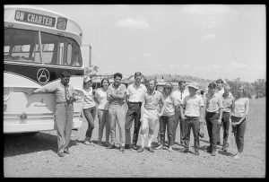 Black and white photograph of protestors standing next to bus.