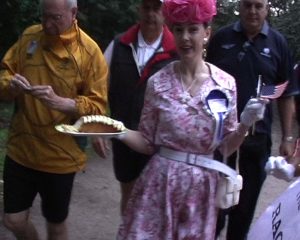 Woman dressed up holding a plate of yellow cake.