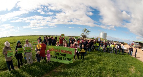 Photograph of a large group of people in a rural paddock. They are holding signs and banners reading 'No Gas Mining on Our Prime Ag Land'.