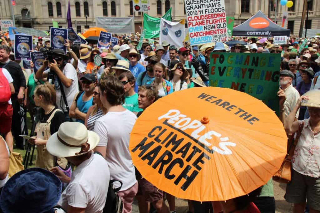people at climate change march with person holding orange parasol with words "we are the people's climate march"