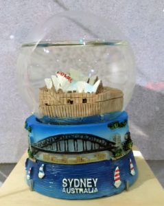 a snow dome that reads Sydney on the bottom. Inside the snow dome is the opera house with NO War written on the top sail of the building.