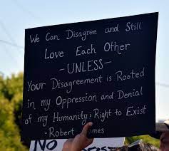 Image of a placard with handwritten text: "We can disagree and love eachother unless your disagreement is rooted in my oppresion and denial of my humanity and right to exist" Robert Jones
