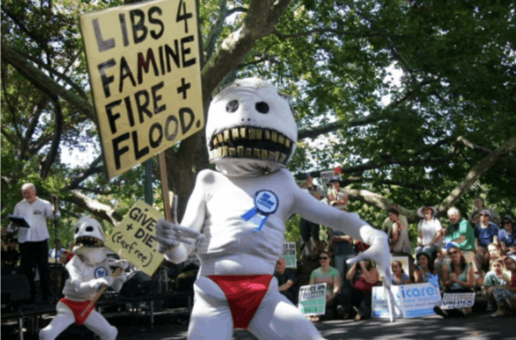 People dressed in costumes with a placard reading 'Libs 4 Famine, Fire and Flood'.