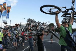Cyclists at a critical mass event hold their bicycles above their heads.
