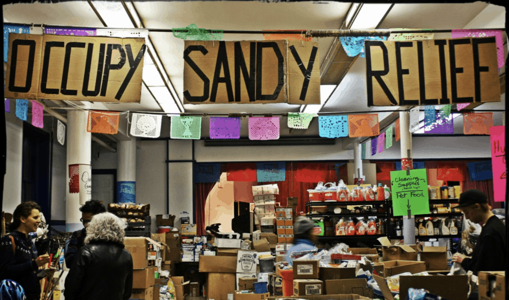 inside a room set up to help with occupy sandy relief. lots of boxes with food and people