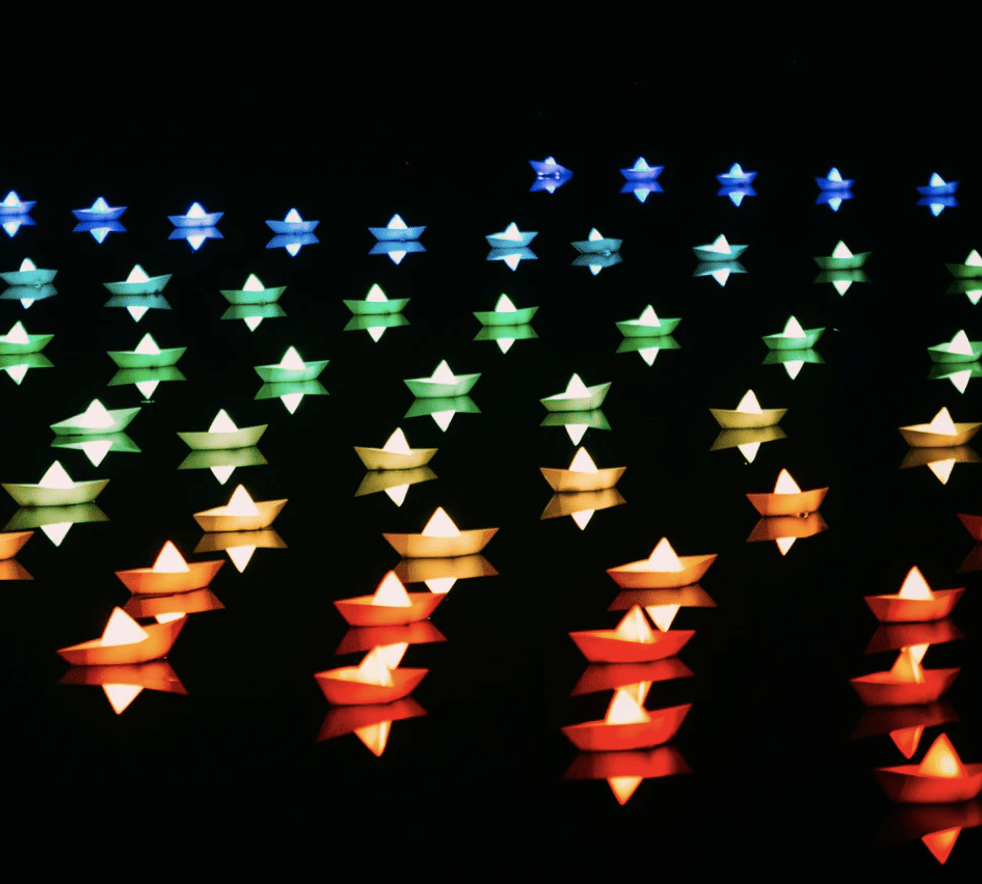 beautifully lit paper boats floating in the dark