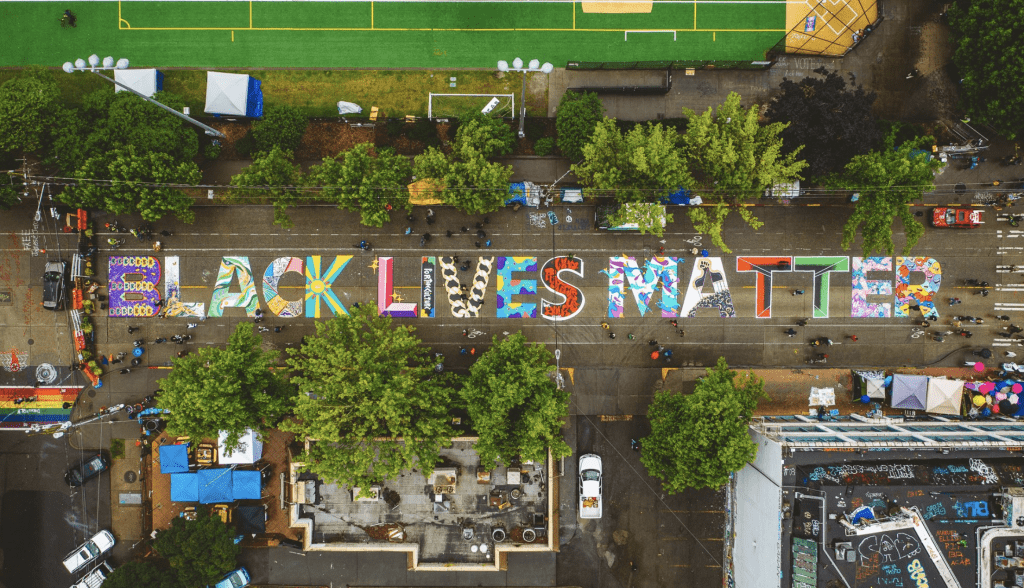 aerial shot of mural that says Black Lives Matter on road in between buildings in Seattle