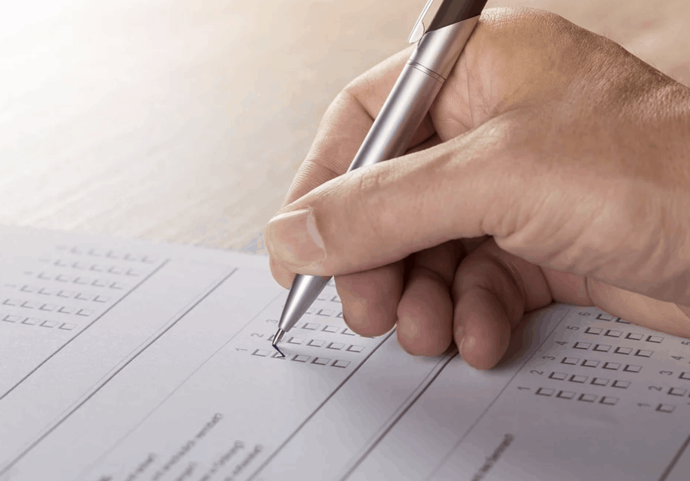 close up of male hand holding pen filling in survey form