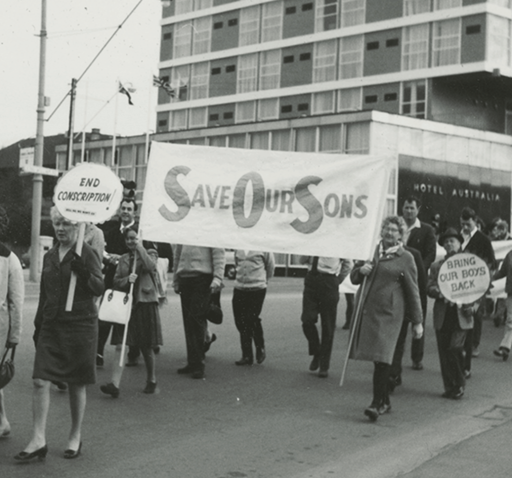 World Peace Day March near the Hotel Australia, King William Street, North Adelaide, 1969. People have signs, which read, "End Conscription", "Save our Sons", and "Bring our boys back".