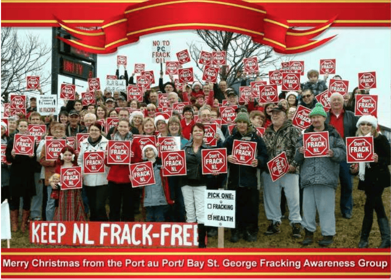 christmas card featuring a group of anti-fracking protestors some with Santa hats on heads holding signs that say Don't Frack NL