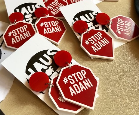 Several pairs of earrings featuring #StopAdani in the shape of a pentagon with a triangle at the bottom