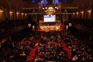 Photograph of inside of Sydney Town Hall filled with people include a large delegation on the stage.