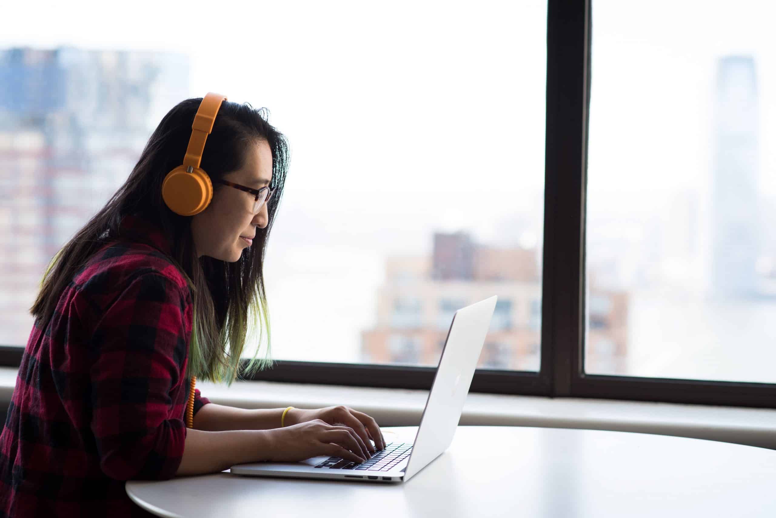 A woman sits at a laptop