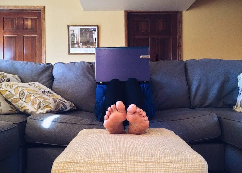 Photo of a person sitting on a couch holding a laptop.