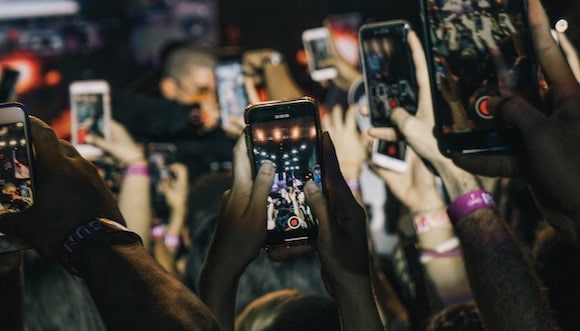 Shallow focus photograph of crowd taking live videos for social media