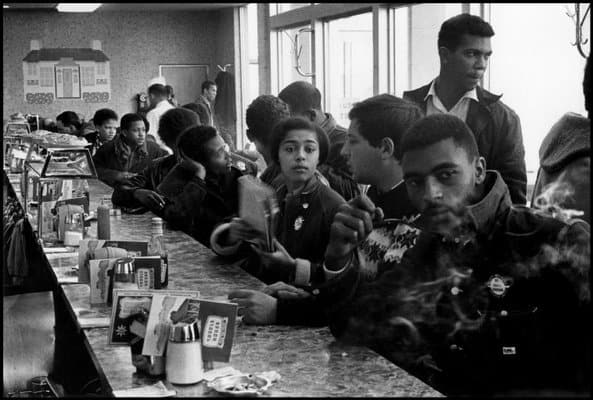A number of African American students sit along a lunch counter.