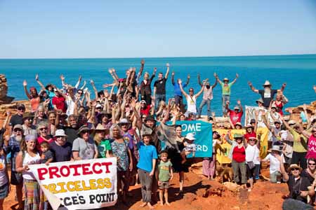A group of people gathered to protest the proposed development at James Price Point|Bob Brown talking at James Price point surrounded by people listening and camera crew