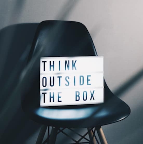 A lit up light box sitting on a black chair saying: Think outside the box