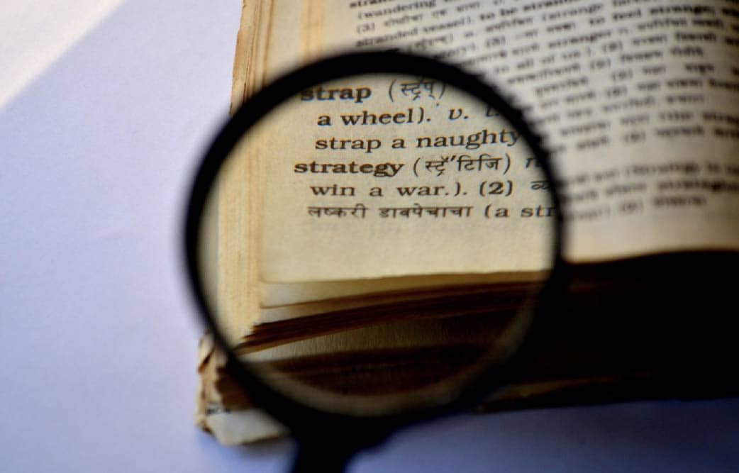 magnifying glass over book - highlighting the word strategy