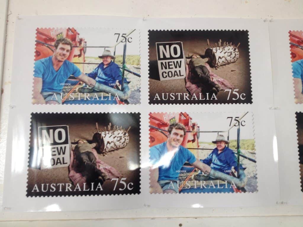 Photograph of stamps featuring 'No New Coal' and two people locked on to disrupt coal production.
