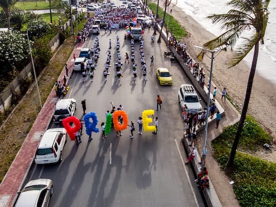 Group of people leading a march with the word pride spelled out using coloured balloons