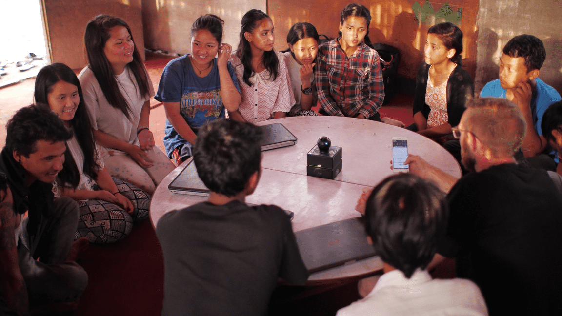 A group of people sit together around a table.