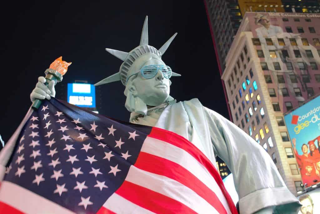 Photograph of someone dressed as the Statue of Liberty draped in the US flag.
