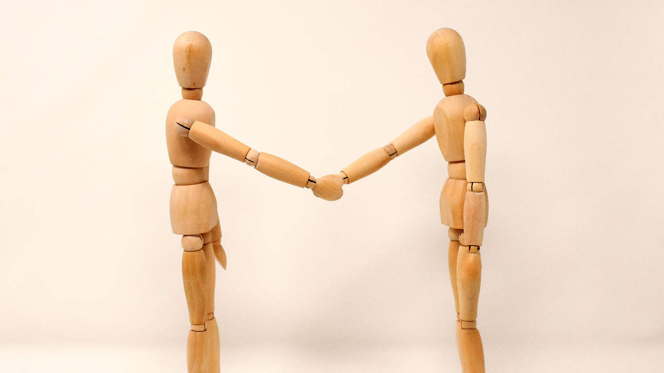 Two wooden art models shaking hands